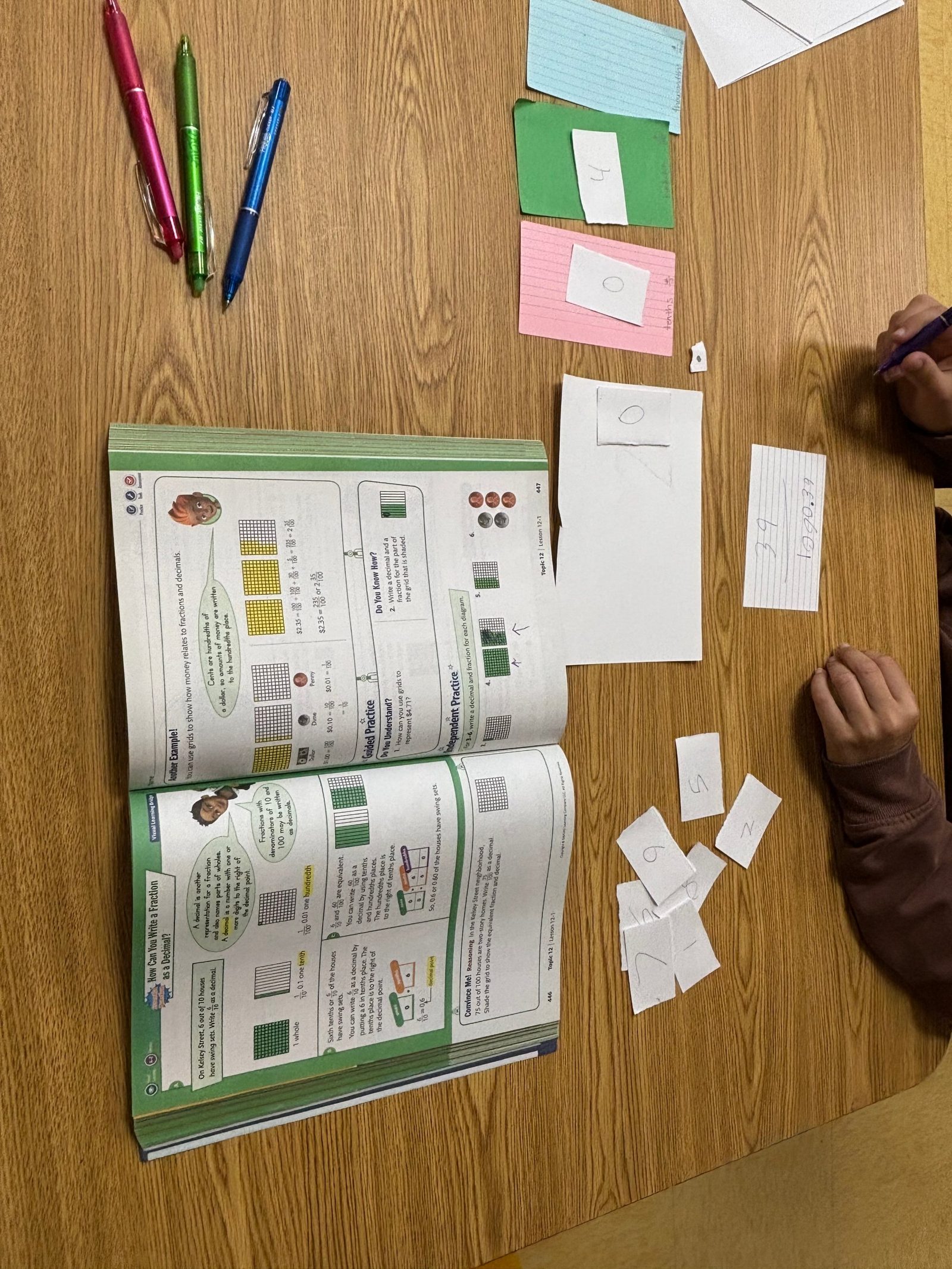 Place-value cards laid out beside a math workbook