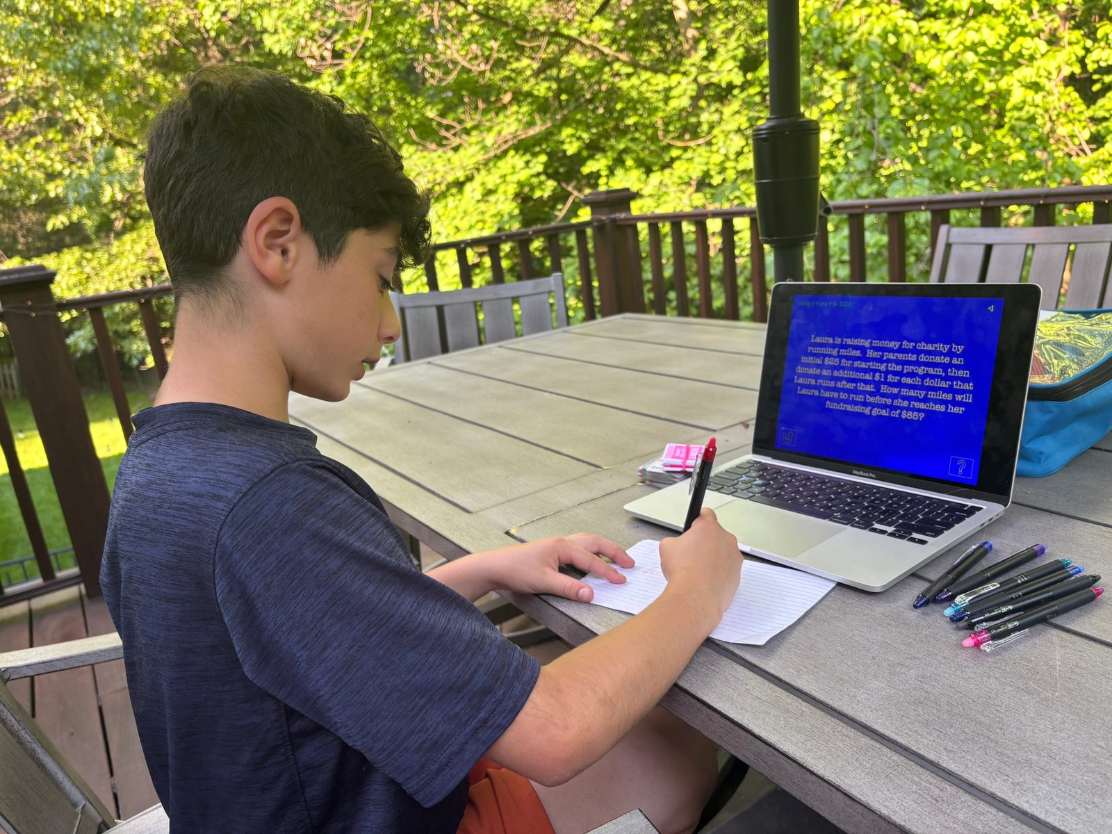 Student working a word problem alongside a laptop lesson