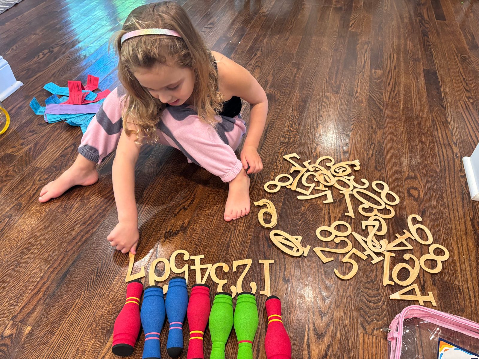 Student ordering wooden numerals on the floor