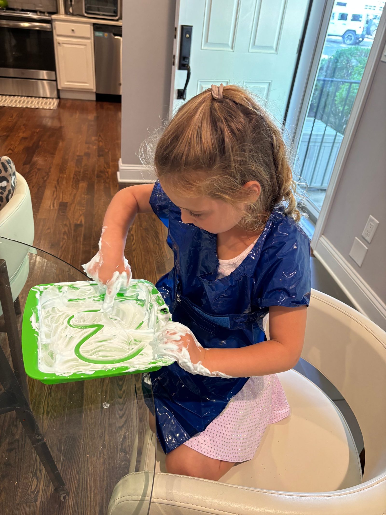 Student forming letters in shaving cream on a tray