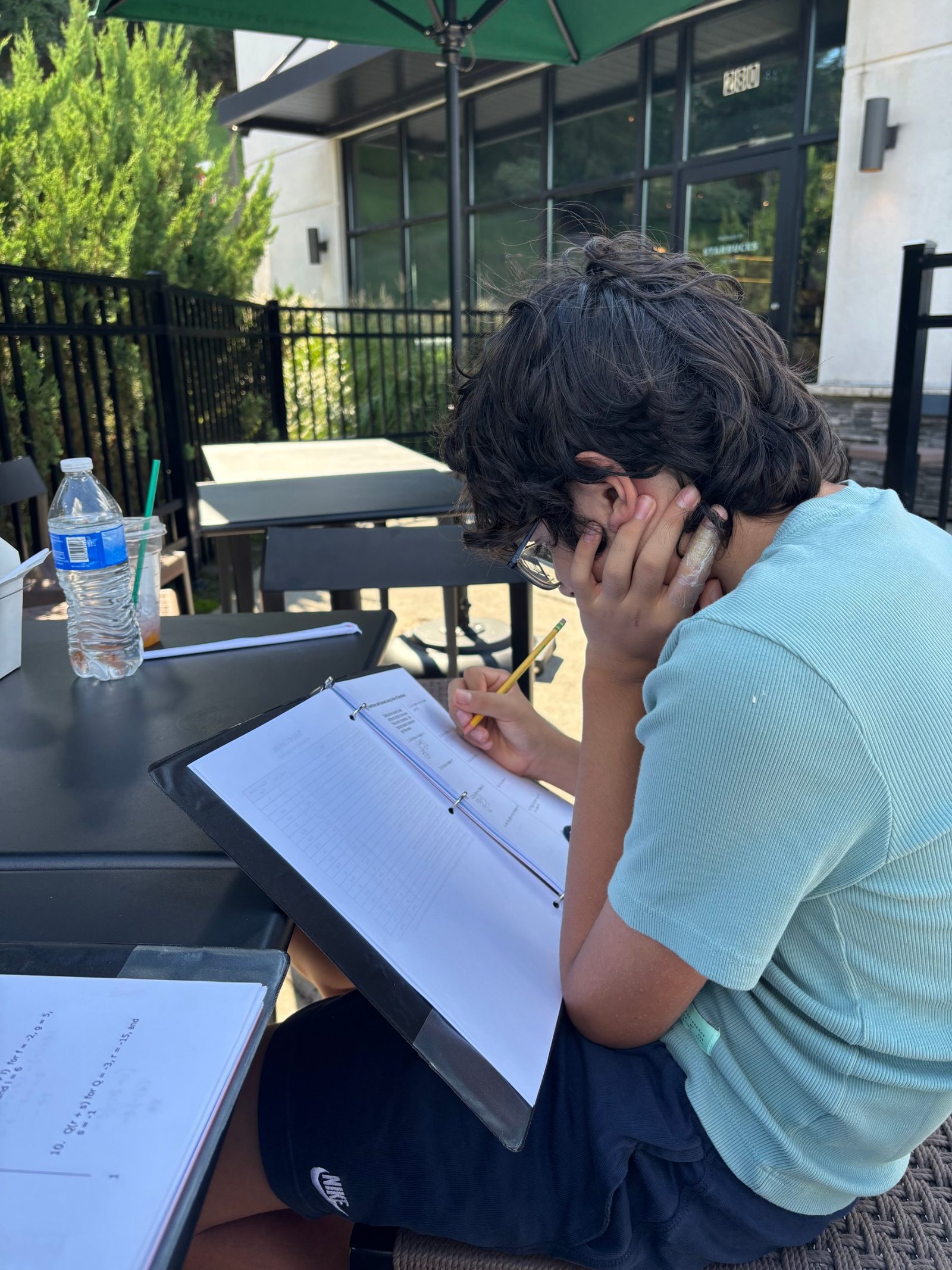 Student working through a problem set at an outdoor table